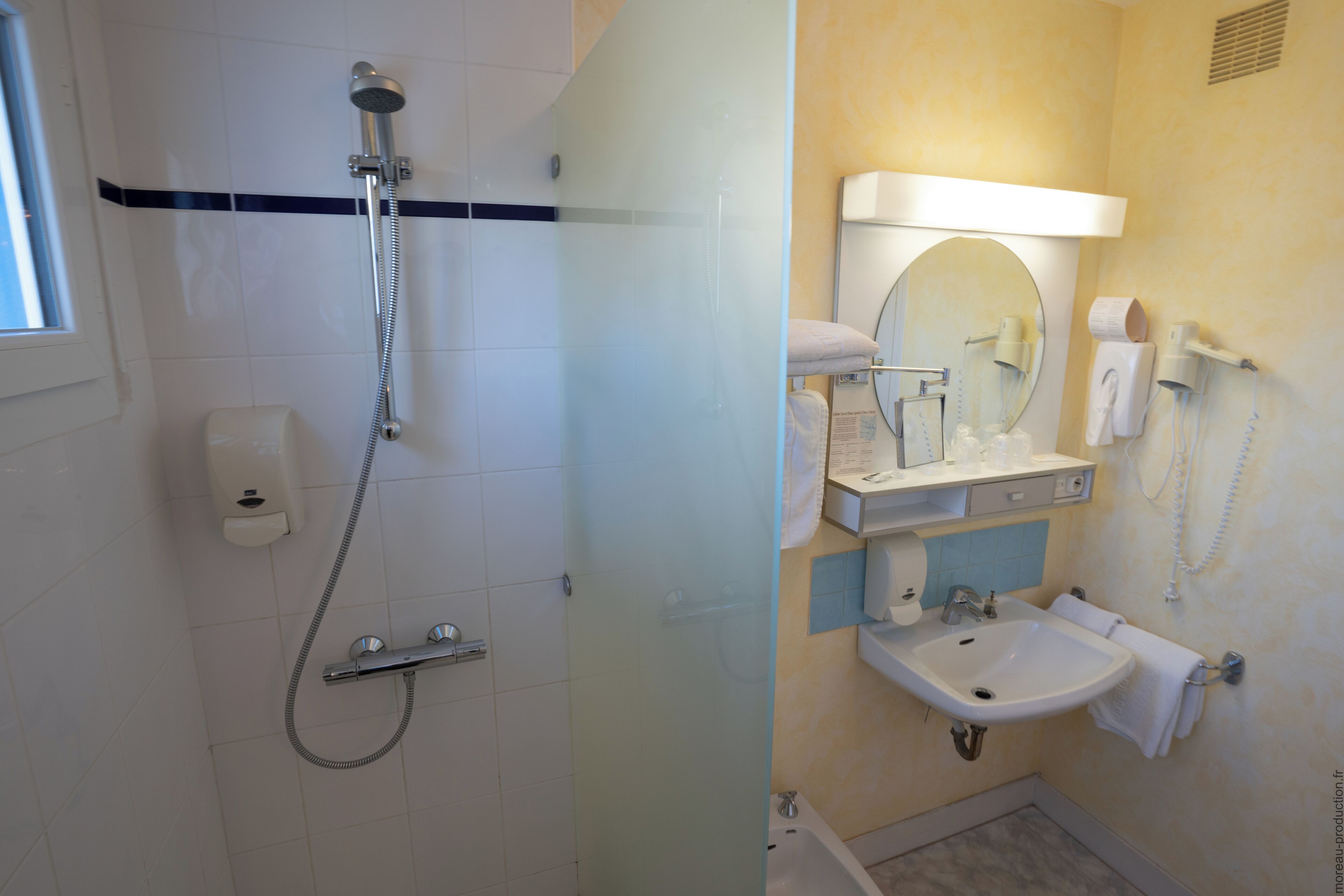 Un bagno con doccia, lavandino, specchio e WC.