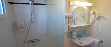 A bathroom with a shower, a sink, a mirror, and a toilet.