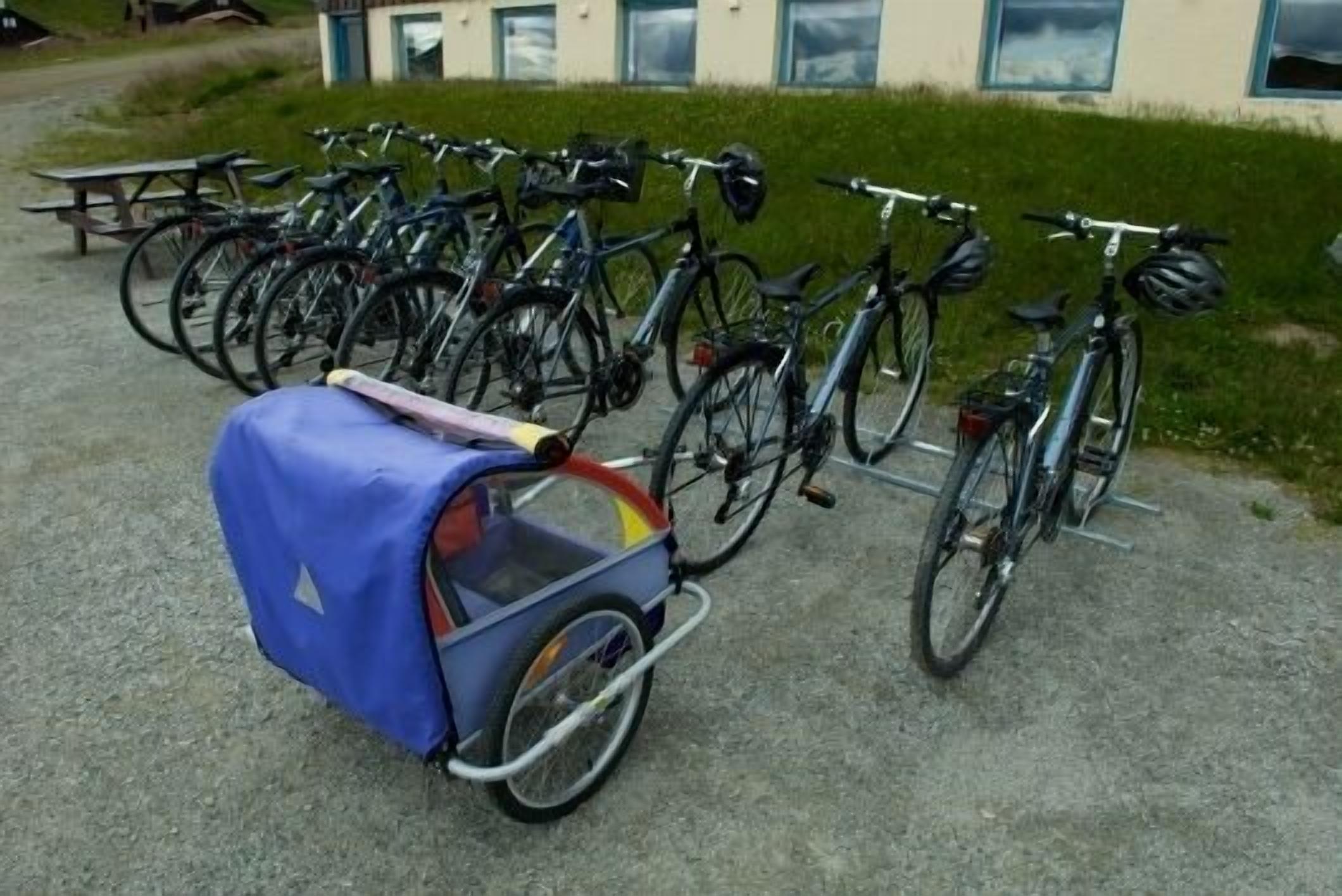 Un vélo recouvert d’une housse bleue est garé à côté d’une rangée d’autres vélos.