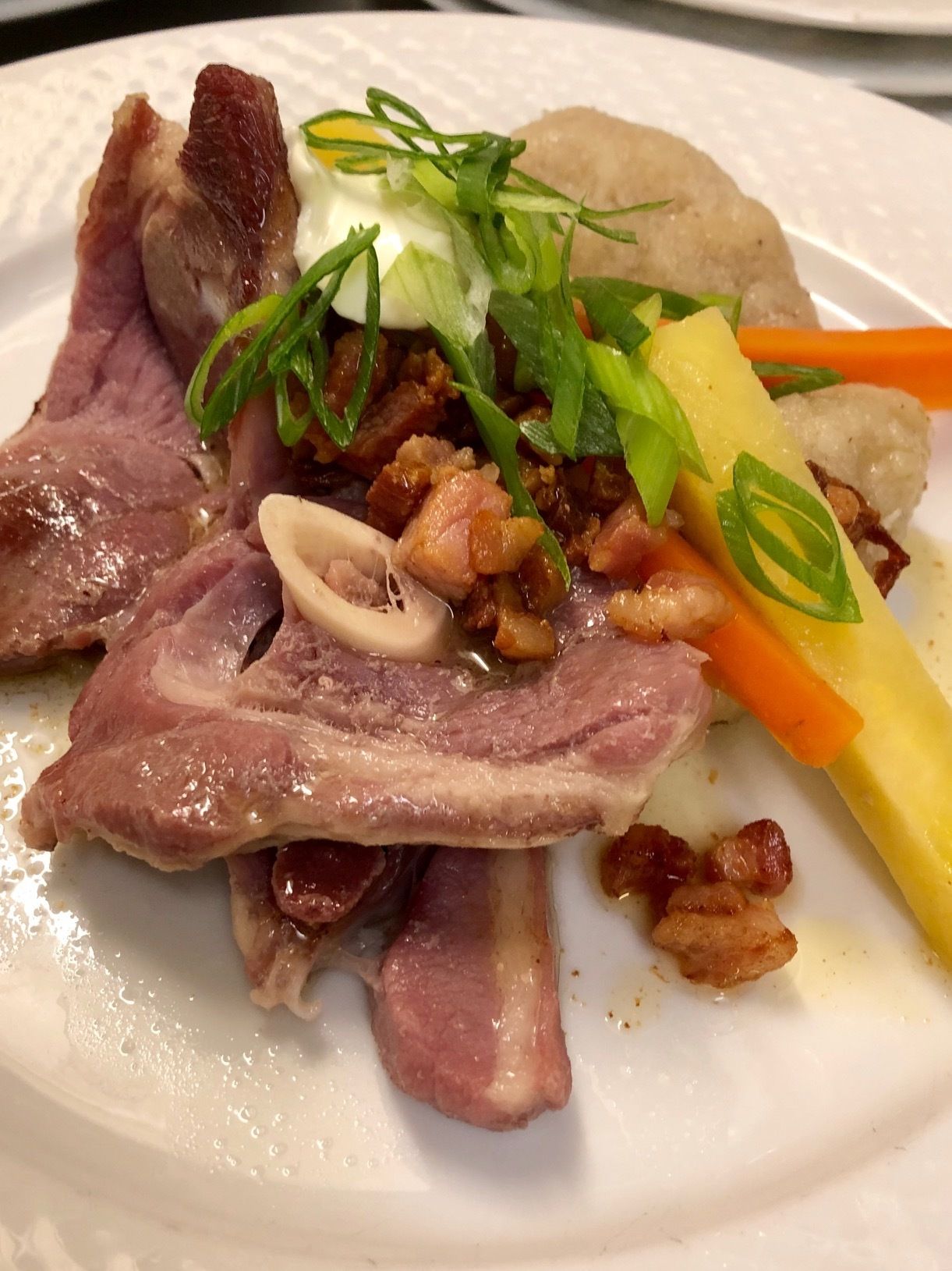 A plate of food with slices of meat, a boiled egg, and garnishes.
