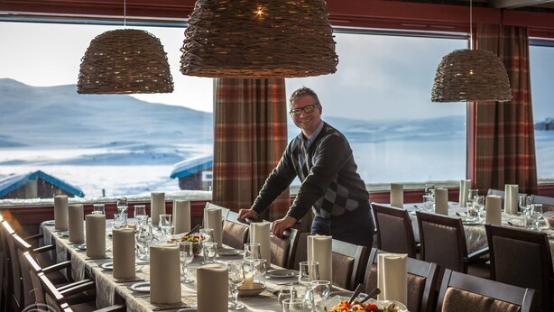 A dining area with a table set for a meal, large candles, and a view of a snowy landscape. - Bergsjøstølen (Al)