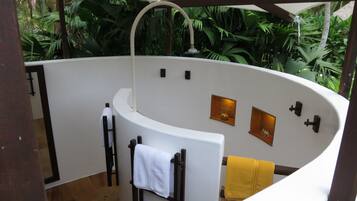 A curved shower area with a white bathtub, a towel rack with a white towel, and a yellow towel.
