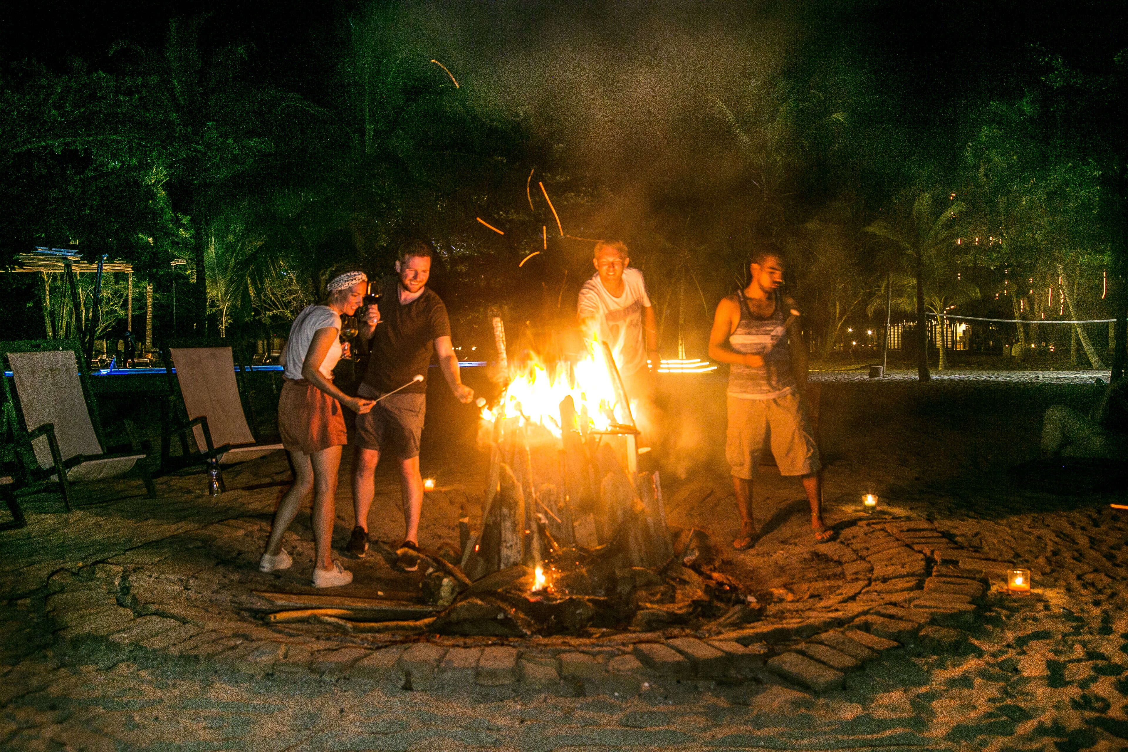 Eine Gruppe von Menschen sitzt an einem Lagerfeuer im Freien.