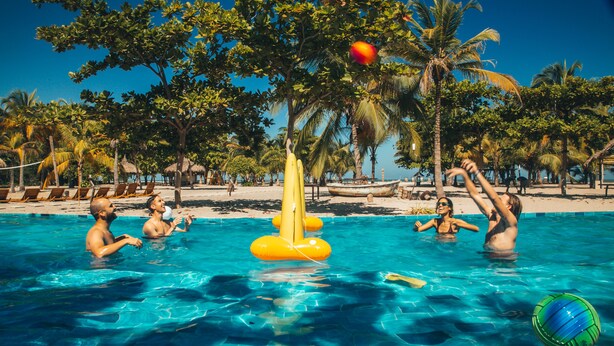A pool area with clear blue water, surrounded by palm trees and lounge chairs. - Viajero Tayrona Hostel & Ecohabs (Santa Marta)