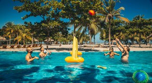 Un espace piscine avec une eau d’un bleu limpide, entouré de palmiers et de chaises longues.