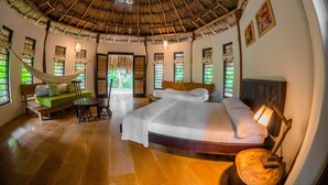 A room with a thatched roof, a bed, a hammock, and a wooden table. - Viajero Tayrona Hostel & Ecohabs (Santa Marta)