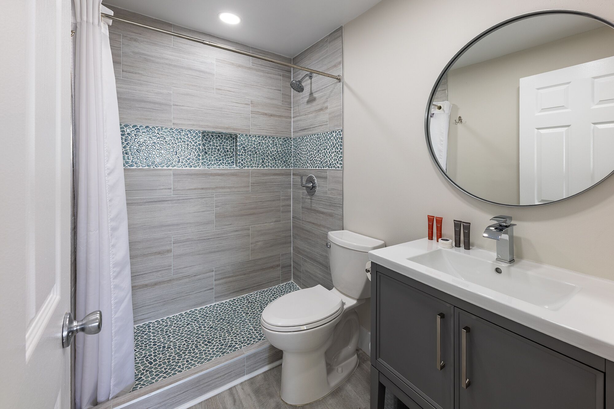 A modern bathroom with a shower, toilet, and sink.