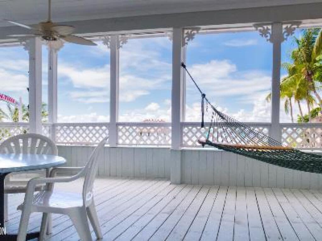 A covered outdoor area with a hammock, a table, and chairs.