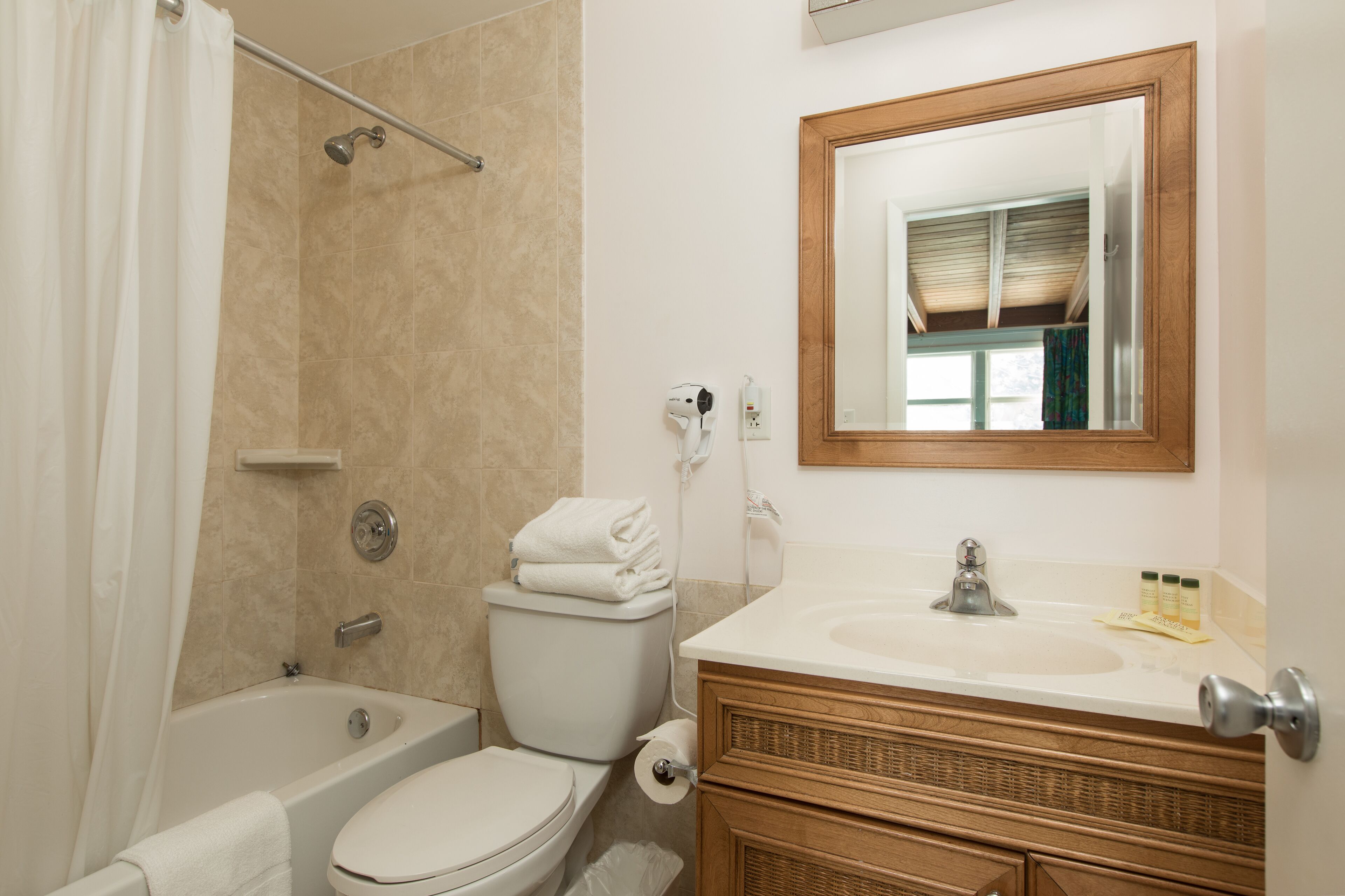 A bathroom with a bathtub, toilet, and vanity with a mirror.