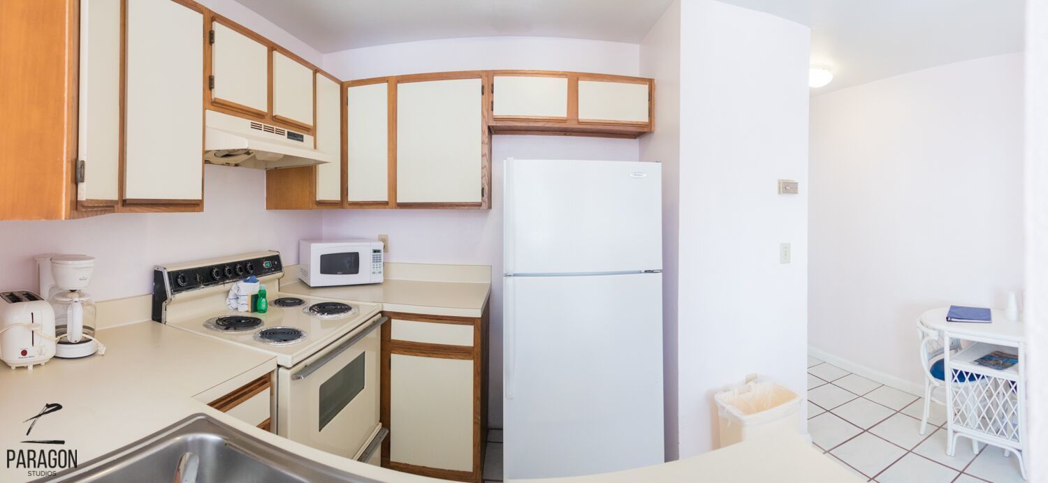 A compact kitchen with a stove, microwave, and refrigerator.