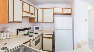 A compact kitchen with a stove, microwave, and refrigerator.