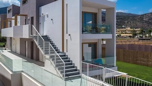 A modern multi-story residential building with a glass balcony, a staircase, and a view of the surrounding landscape. - Meropi Hotel & Apartments (Hersonissos)