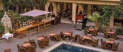 An outdoor dining area with wicker furniture and a pool.