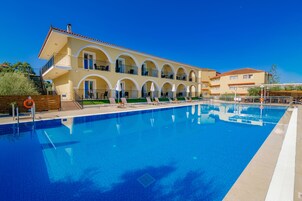 Un hotel con piscina, area salotto all'aperto e patio coperto.