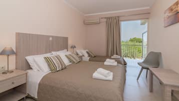 A hotel room with a large bed, a desk, a chair, and a balcony with a view.
