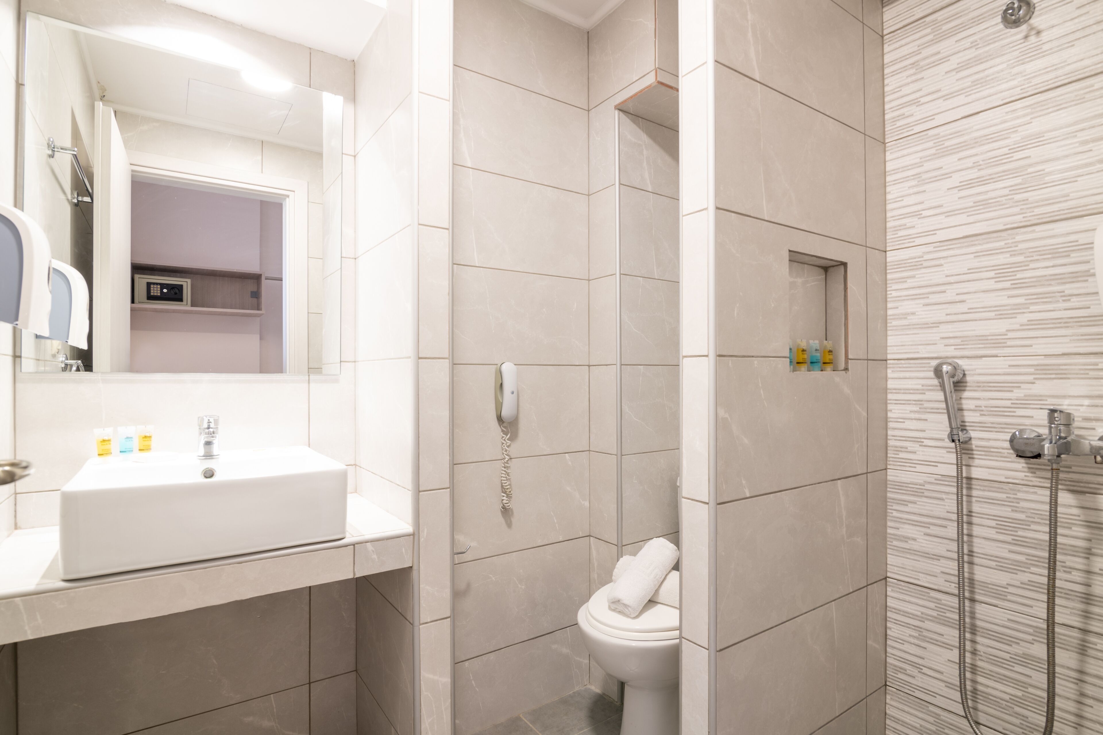 A modern bathroom with a white sink, a toilet, and a shower area.