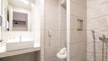 A modern bathroom with a white sink, a toilet, and a shower area.