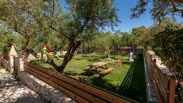 Relax in a serene outdoor space surrounded by mature trees and a lawn.