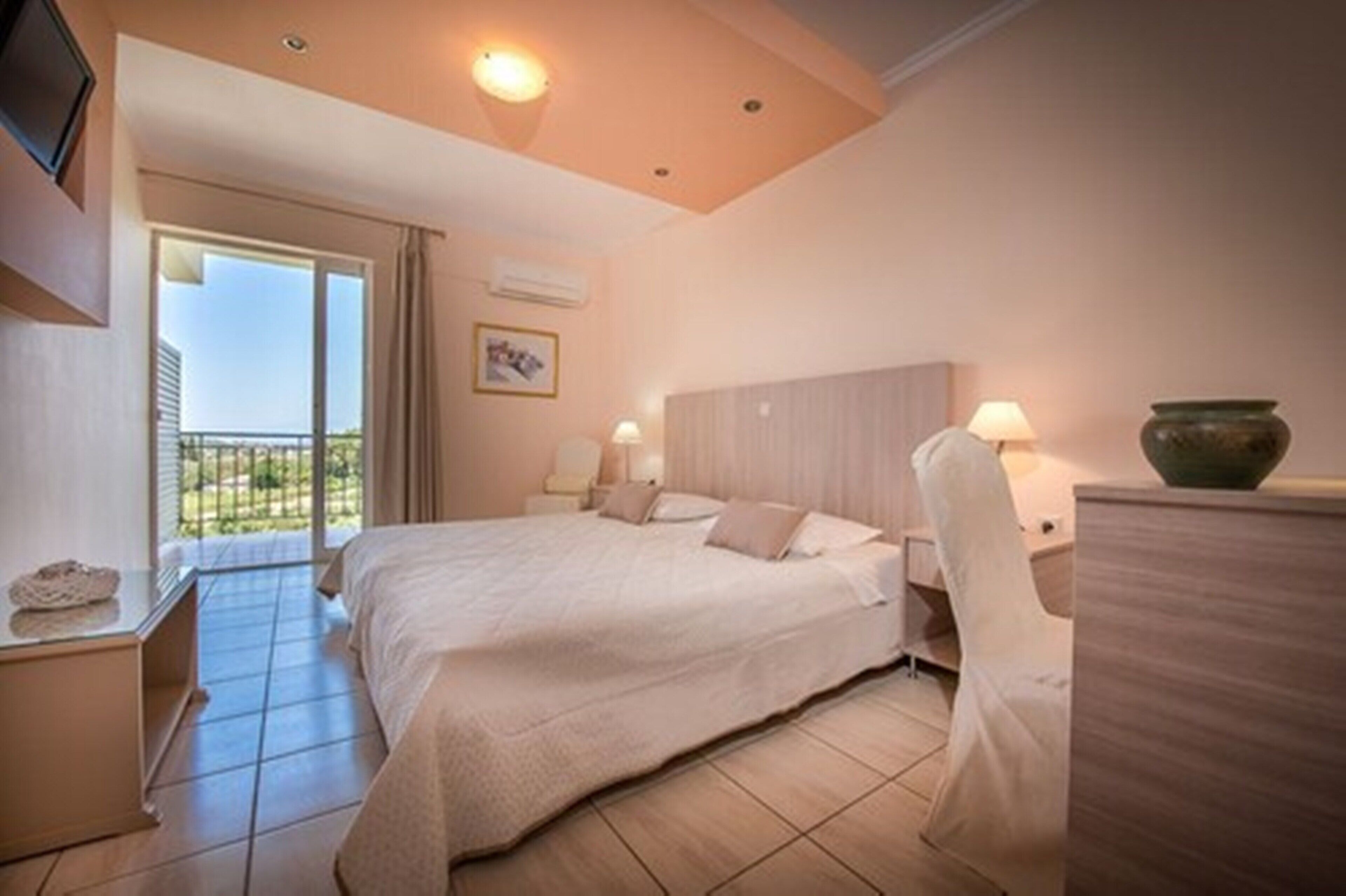 Habitación de hotel con una cama grande, un escritorio, una silla, una lámpara y vistas al exterior.