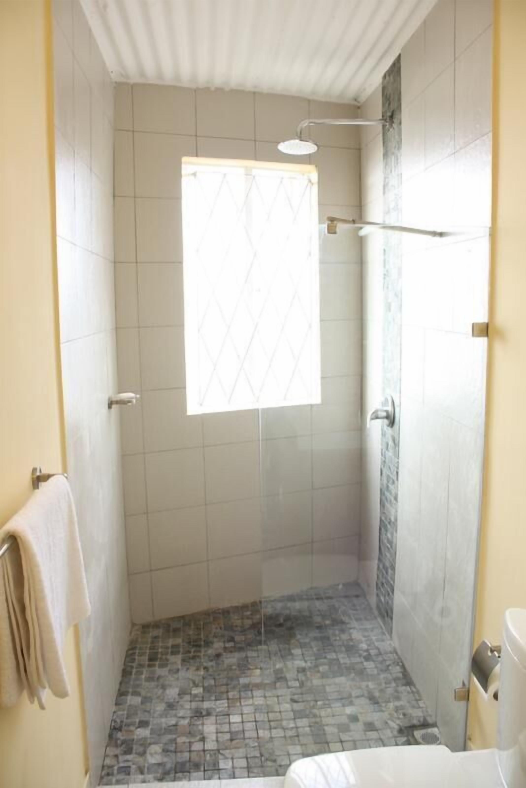 Un piccolo bagno rivestito di piastrelle, con finestra, asciugamano e WC.