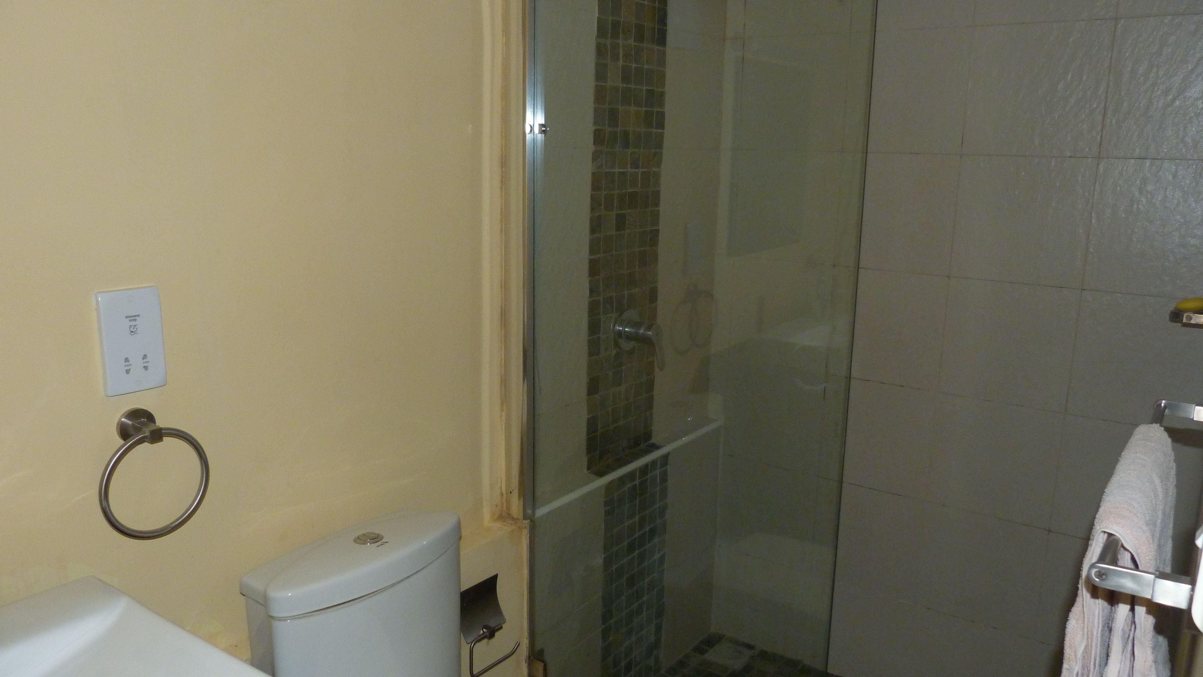 A bathroom with a toilet, a glass shower enclosure, and a towel rack.
