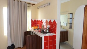 Una cocina compacta con estufa a gas, pileta y un salpicadero de azulejos rojos.