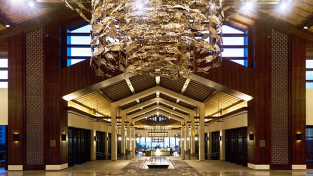 Un hall d’entrée spacieux avec un plafond haut, une fontaine centrale et une vue sur le paysage urbain grâce à de grandes fenêtres.