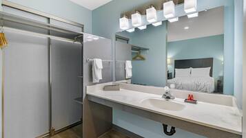 A modern bathroom with a walk-in shower, a large mirror, and a vanity with a sink.