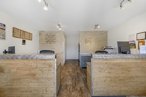 A reception area with wooden reception desks, a wall-mounted decorative piece, and a framed picture. - SureStay by Best Western Yerington (Yerington)