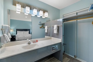 A modern bathroom with a large mirror, a white sink, and a shower area. - SureStay by Best Western Yerington (Yerington)
