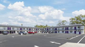 A motel with a parking lot, multiple vehicles, and a clear sky.