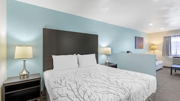 Habitación de hotel con cama, dos mesitas de noche, escritorio, silla y ventana con cortinas.