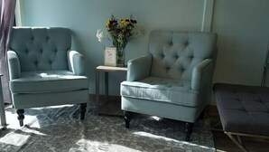 A living room with two light blue armchairs, a patterned rug, and a wooden floor. - SureStay by Best Western Yerington (Yerington)