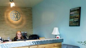 A reception desk with a wooden panel design, a blue wall, a clock, and a motivational quote sign. - SureStay by Best Western Yerington (Yerington)