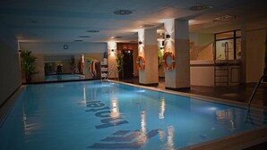 An indoor swimming pool with a lifebuoy on each pillar, a changing room, and a reception area. - Economy Silesian Hotel (Katowice)
