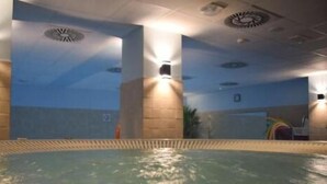 An indoor swimming pool with clear water, surrounded by walls and pillars, and a ceiling with recessed lighting. - Economy Silesian Hotel (Katowice)