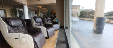 Un área de espera moderna con sillones de cuero, un mostrador de recepción y vistas a la terraza exterior.