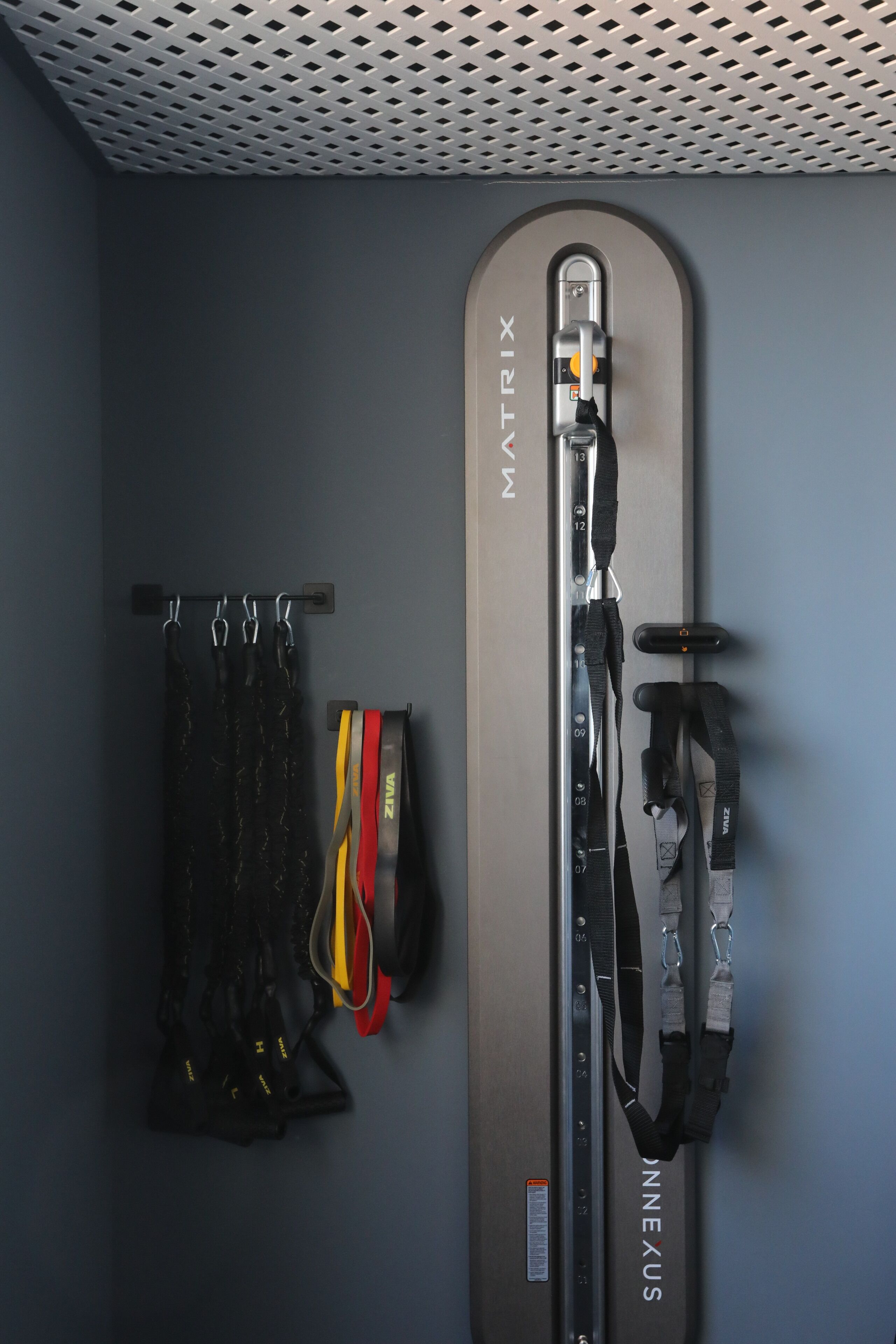 Una habitación con una pared gris, una puerta que dice 'Matrix' y un perchero con varias correas.