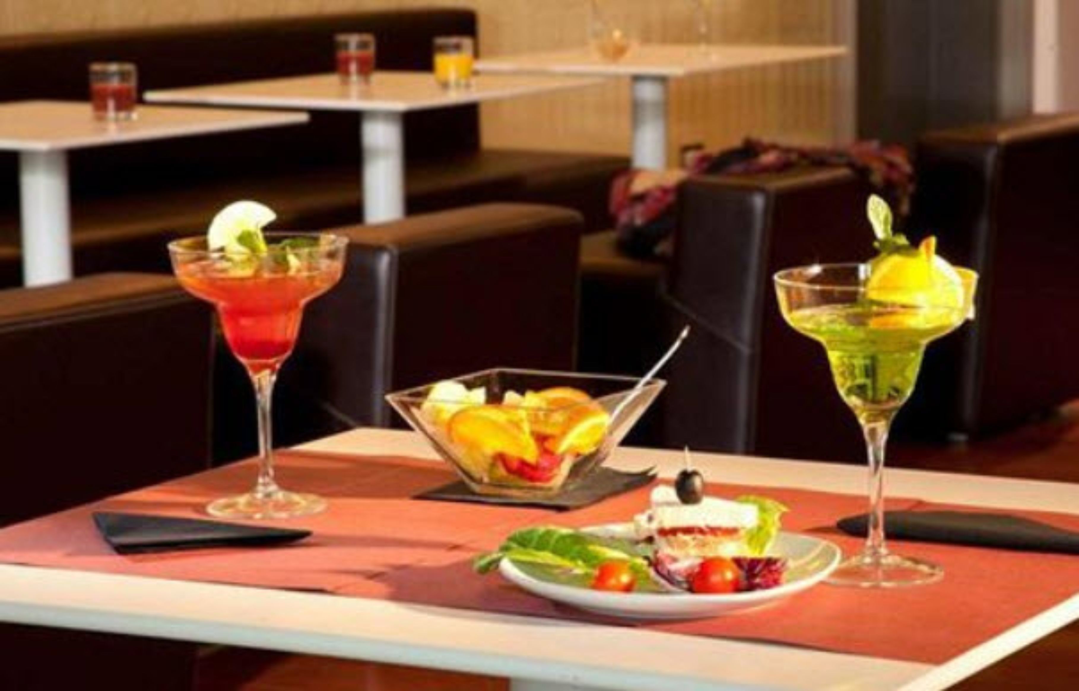 Un ambiente de restaurante con mesas, sillas y una variedad de bebidas y alimentos.
