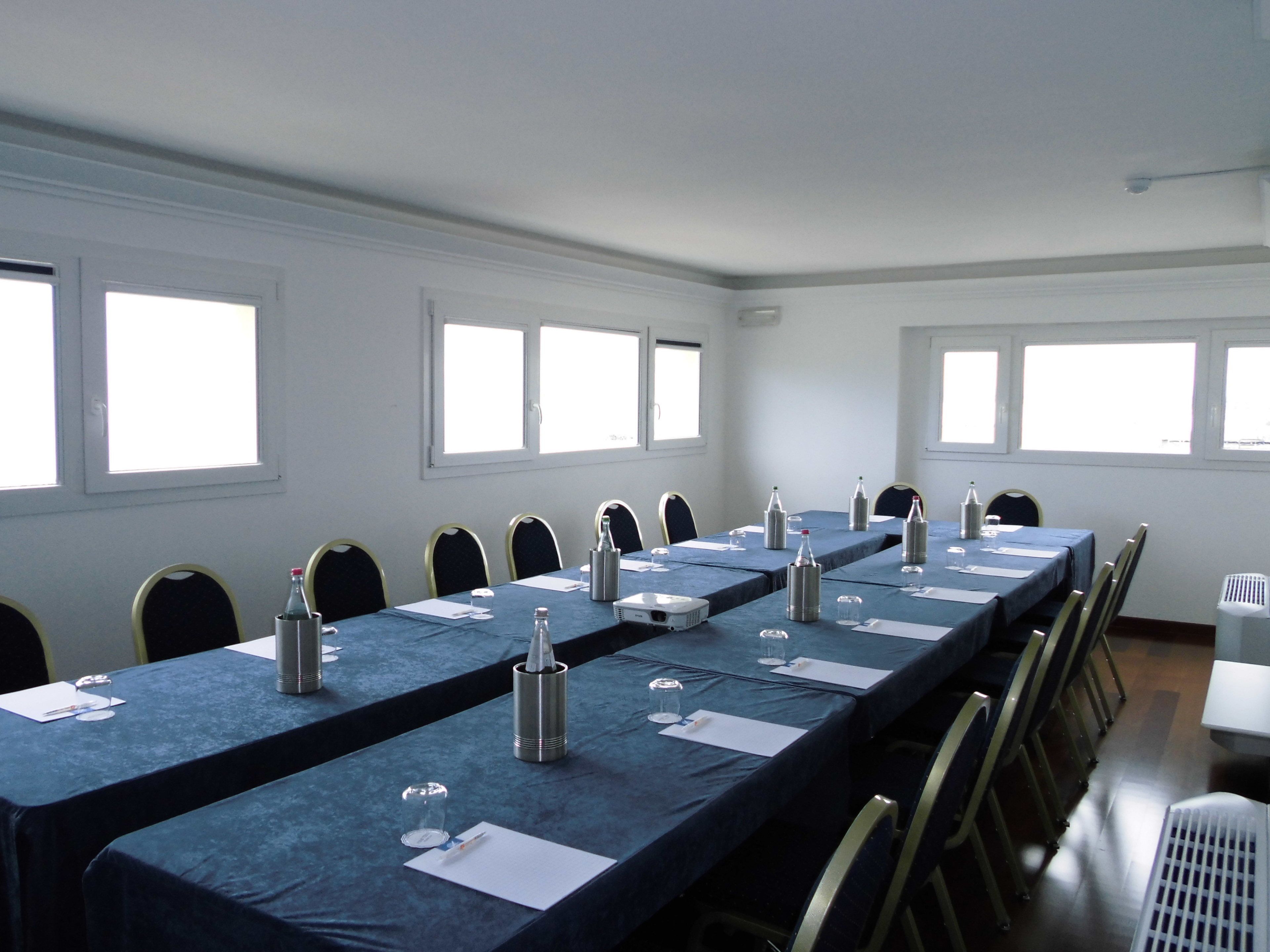 Un salón de conferencias con una larga mesa, sillas y un proyector.