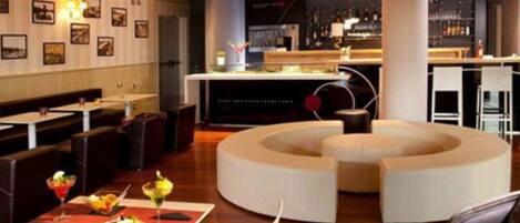 A modern bar area with a curved seating arrangement, a counter with a menu, and a wall with framed pictures.