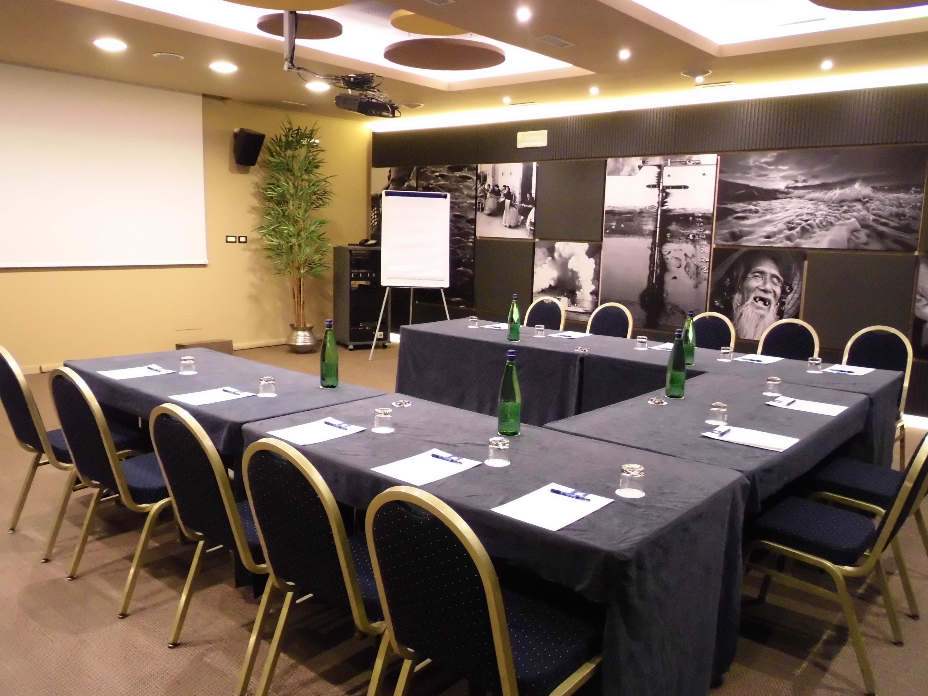 A conference room with tables, chairs, a projector, and a whiteboard.