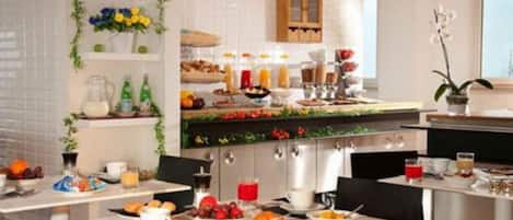 Um buffet de café da manhã com diversos alimentos e bebidas, um espaço com café e uma parede decorada com flores.