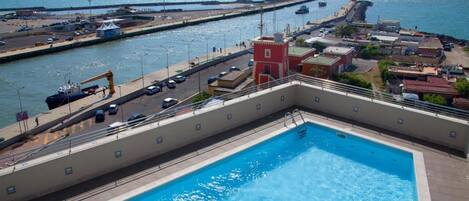 A swimming pool with a view of the sea and a pier in the background.