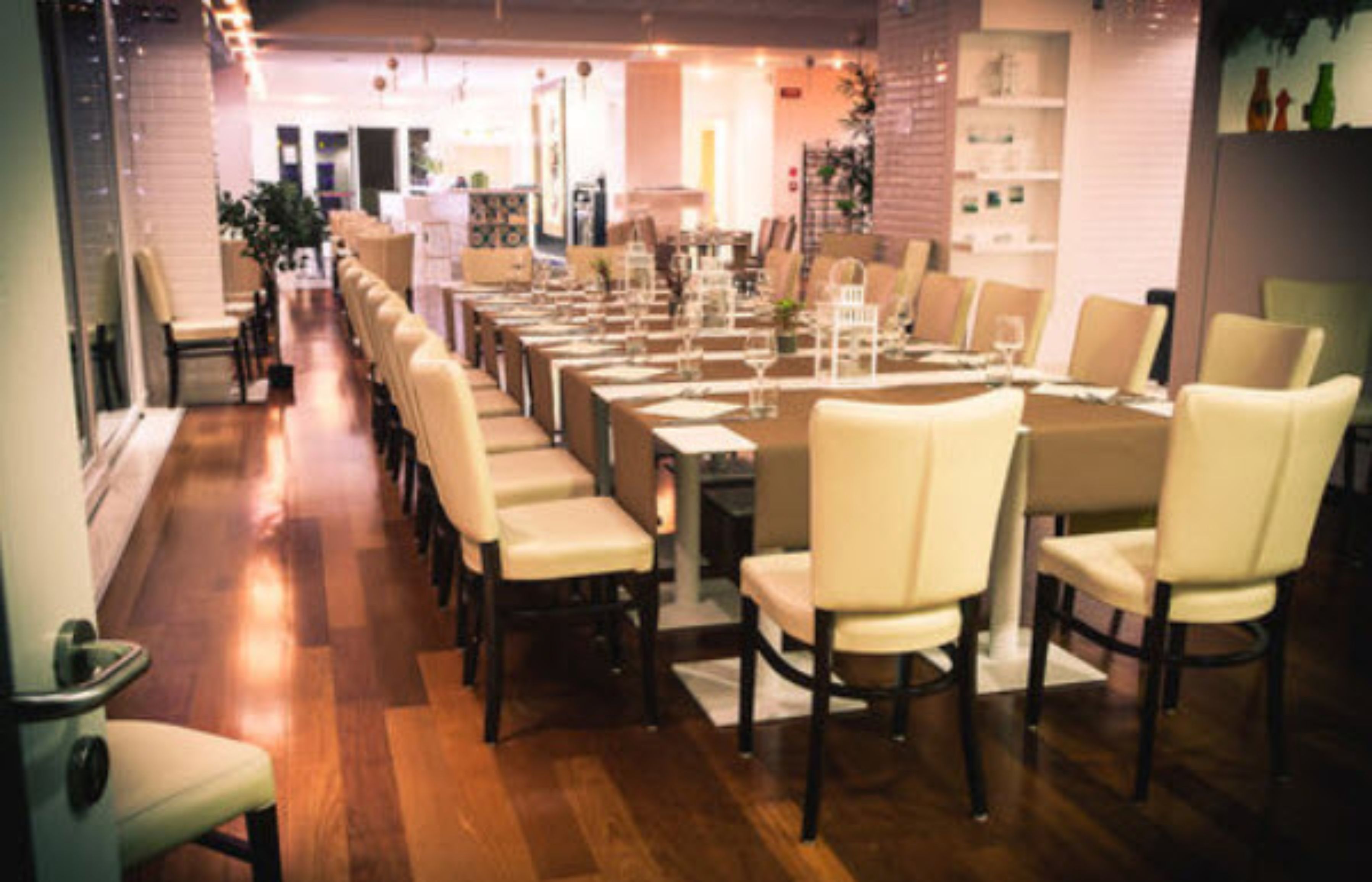A restaurant with a long dining table set for a meal, surrounded by chairs.