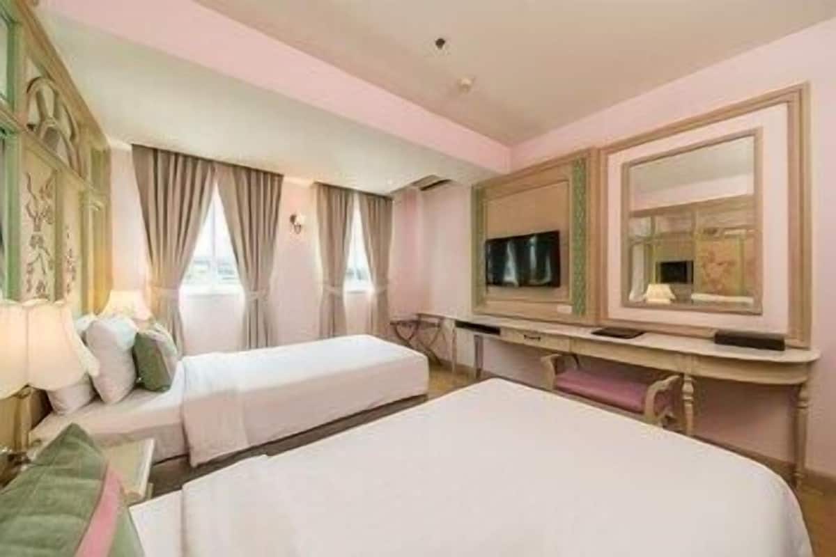 A hotel room with two beds, a desk with a television, and a large mirror.