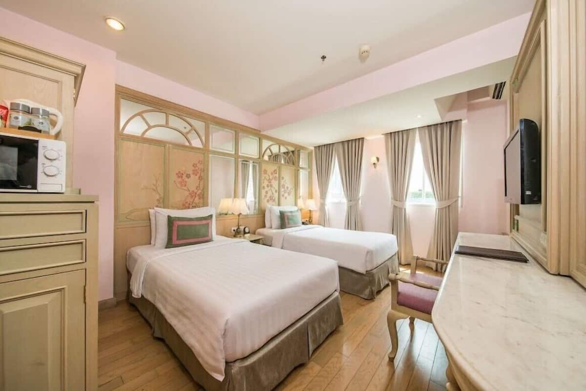 A hotel room with two beds, a TV, a desk, and a kitchenette with a microwave and kettle.