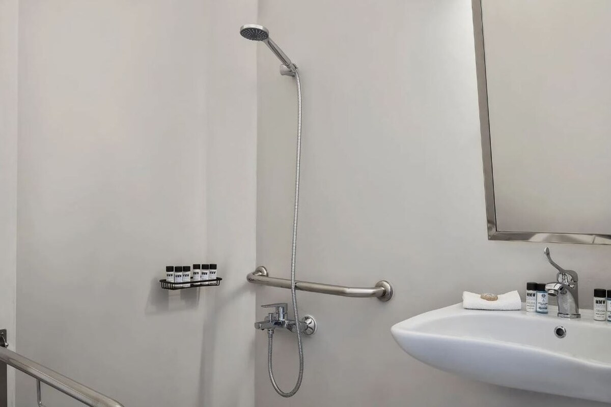 Ein Badezimmer mit Dusche, Waschbecken und Handlauf.