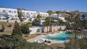 Et resort med hvide bygninger, en swimmingpool og palmer.