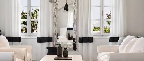 A modern living room with white furniture, a white coffee table, and black and white curtains.